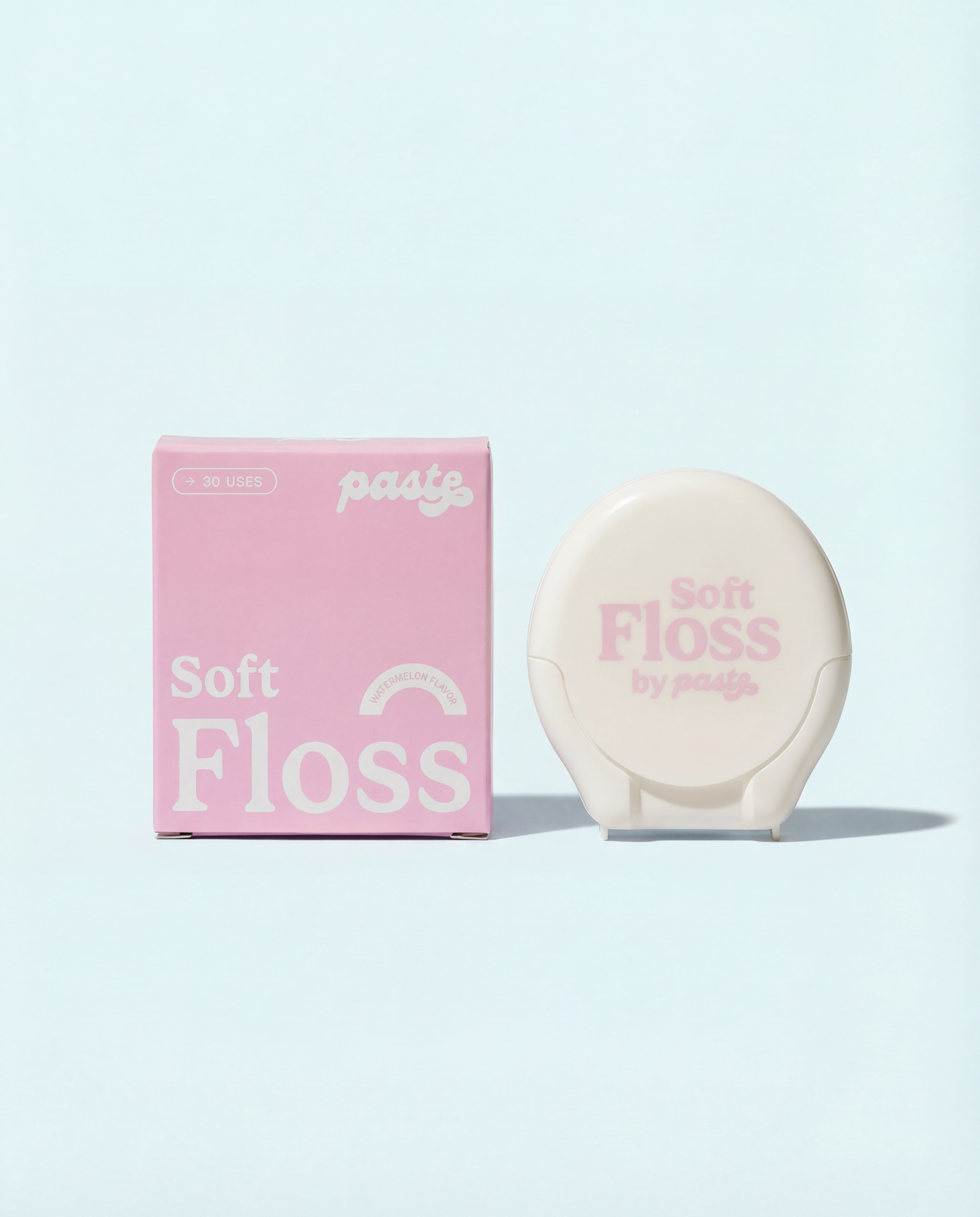 Pink box and cream-colored compact for Paste Soft Floss in Watermelon flavor (30 uses) displayed side by side on a pale blue background.