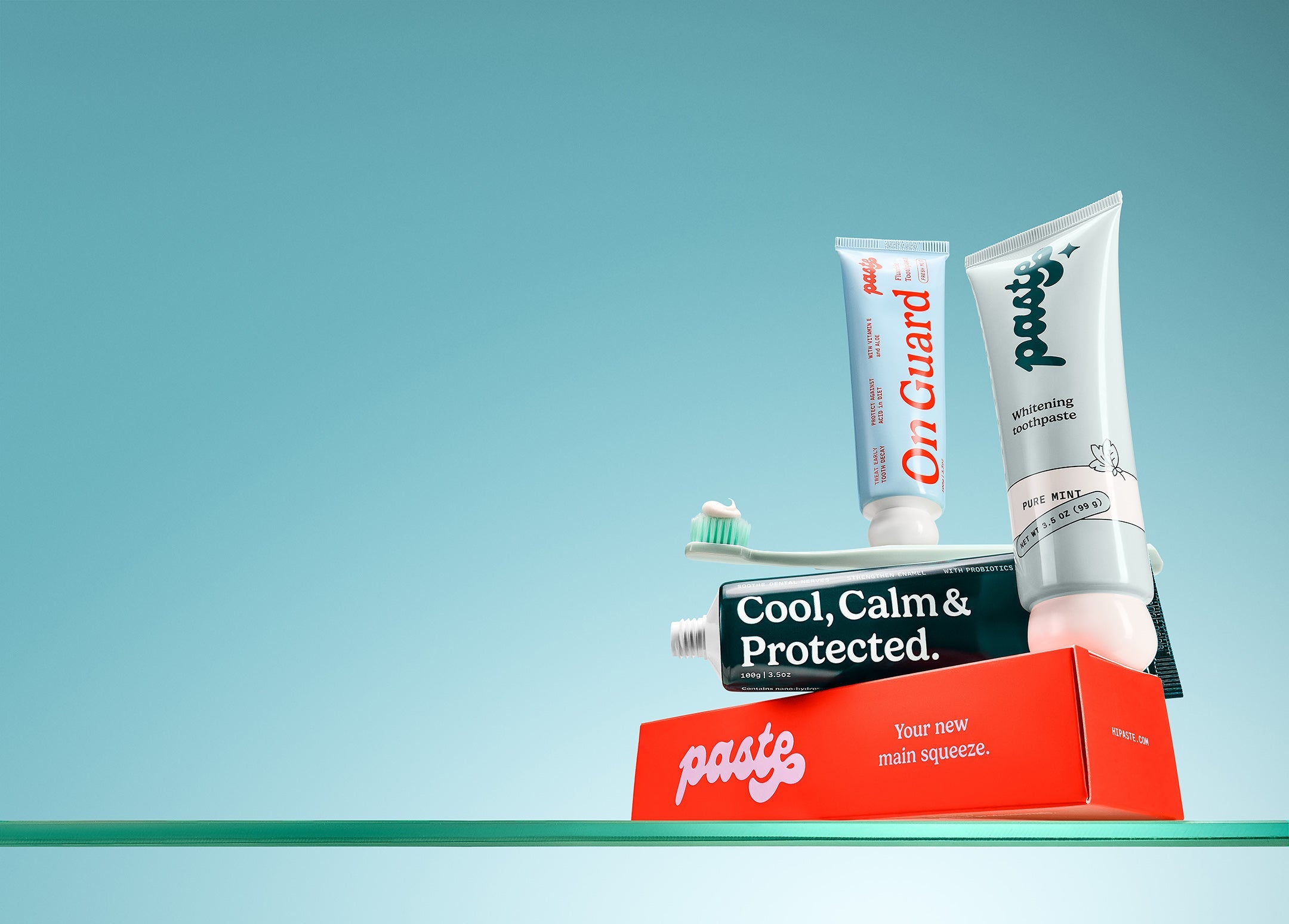 Paste sensitivity toothpaste, Paste fluoride toothpaste, Paste whitening toothpaste and toothbrush on a glass bathroom counter.