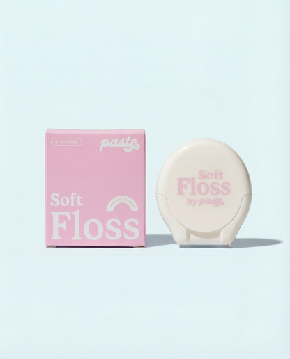 Pink box and cream-colored compact for Paste Soft Floss in Watermelon flavor (30 uses) displayed side by side on a pale blue background.